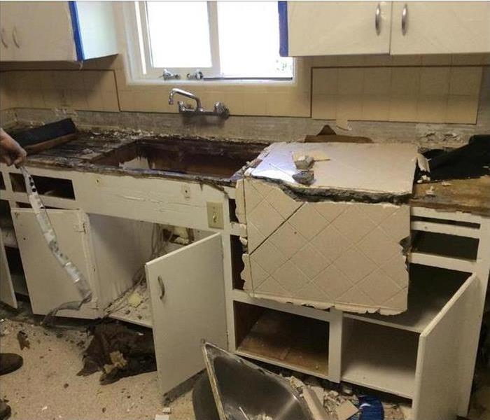 broken countertop, sink on floor, water damaged white cabinets