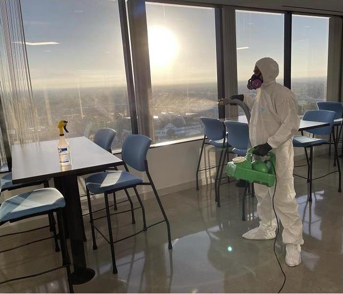 SERVPRO tech, donned in PPE, applying a sanitizing fog to commercial space