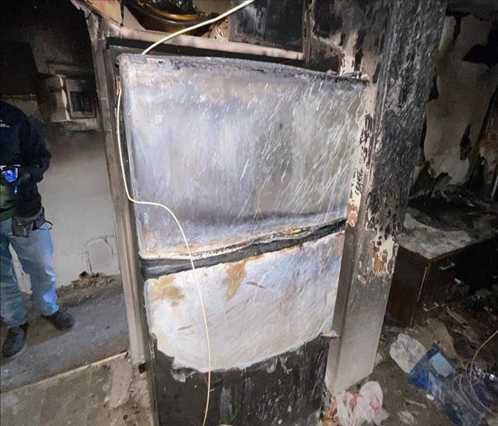 Heavy charring on kitchen walls, overhead cabinet, and refrigerator