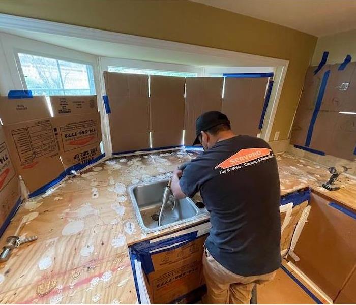 SERVPRO technician in front of a kitchen counter with countertops removed